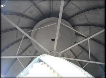 Photograph showing black, riveted inside of dome roof. Top of lighthouse lens can be seen at bottom of image