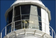 Photograph showing glass glazing panes fitted in lantern house. Lighthouse lens can be seen behind glass inside lantern room.