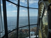 Photograph showing glass glazing panes from inside lantern house. Sea can be seen through the panes, and lighthouse lens can be seen in front of panes on right hand side. 