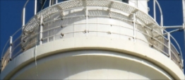 Photograph showing white balcony surrounding lantern house. White handrails ring the balcony.  