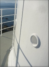 Photograph showing external wall of lantern house. White wall has round indent for ventilation.  