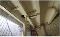 Photograph showing underside of lantern house floor. Cream-coloured floor, consisting of slabs sitting on iron beams, is supported by two columns.  