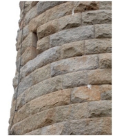 Photograph showing external face of the light brown granite walls of the lighthouse. The walls consist of rough-hewn stones. 