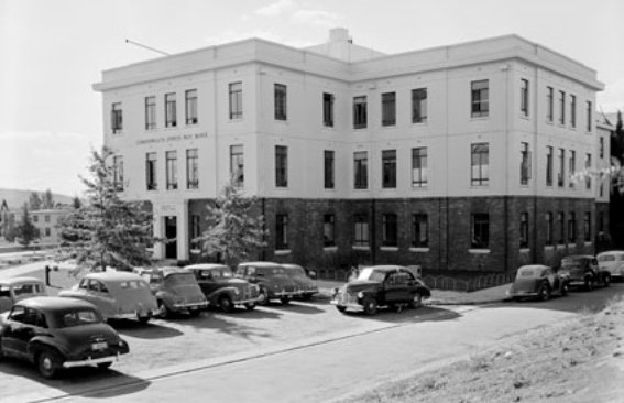 Cars parked outside a three storey brick and render building.