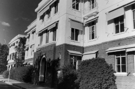 Entrance to a building with windows either side and above.  Windows have pull-down awnings attached above.