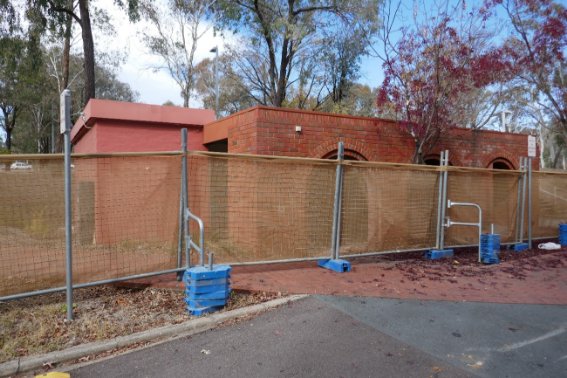 Single storey red brick screen wall with three arches.