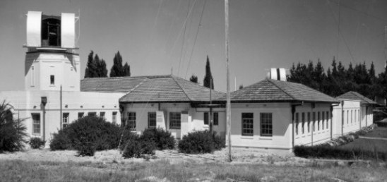 A single storey, hipped roof building with a tower to the left.