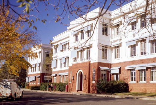 Three-storey building with an arched entrance and rows of windows with drop-down blinds.