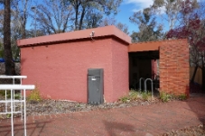 A small rectangular brick building with a red brick screen wall.