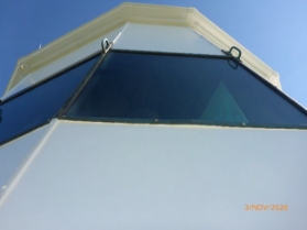 Photograph showing close up of glazing panes and white blanking panels attached that surround the lantern room.