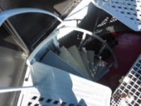 Photograph showing cast iron spiral steps leading from cast iron lattice floor to red floor below.