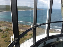 Photograph showing curved glazing fitted within frames. Blue ocean and coastline can be seen through glazing outside.