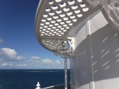 Photographs showing curved, white lattice catwalk, fixed around curved white wall. Ocean can be seen in background.