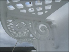 Photographs showing section of curved white lattice catwalk, with close up shot of ornate bracket fixed to curved white wall behind.