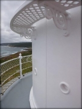 Photographs showing external, curved, lantern room wall panels. A Lattice catwalk and narrow balcony wraps around the walls. Ocean can be seen below.