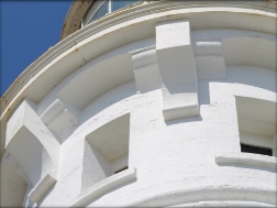 Photograph showing external face of round, white stone room with cornices and window ledges.