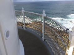 Photograph showing curved, narrow balcony floor with white balustrades wrapped around edge of balcony.