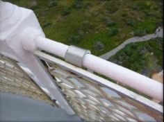 Photograph showing white balustrade pipe rail with aluminium mesh grille fitted onto railing.