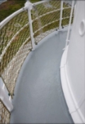 Photograph showing curved, narrow balcony floor with white balustrades wrapped around edge of balcony.