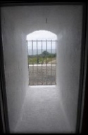 Photograph showing window opening cut into thick stone wall with external grilles fitted to outside of opening.