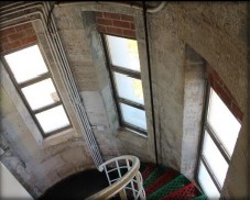 Photograph showing round brick room with three large windows cut into brick.