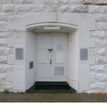 Photograph showing a white door cut into stone walls.