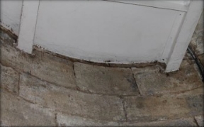 Photograph showing underside of white floor embedded in curved stone wall.
