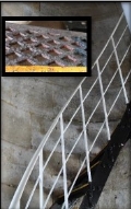 Photograph showing black, cast iron staircase with white wrought iron railing and stanchions. wrapped around stone wall.