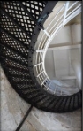 Photograph showing black, cast iron staircase with white wrought iron railing and stanchions. wrapped around stone wall.