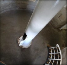 Photograph showing concrete slab with white tube fitted to centre of floor.