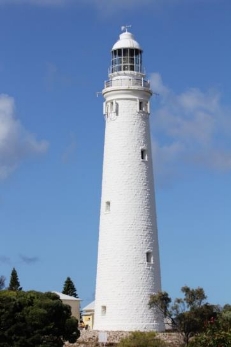 Photograph showing tall white lighthouse tower with lantern house against blue sky.