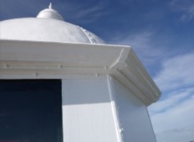 Photograph of lantern roof gutter against blue sky. 