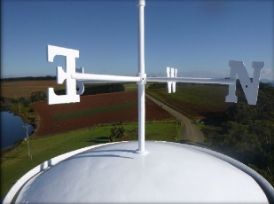 Photograph showing white weathervane against blue sky.