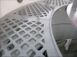 Photograph showing grey, curved lattice floor panels running along edge of lantern room. 