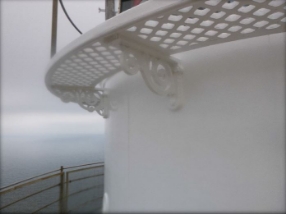 Photograph showing underside of white, curved lattice floor panels fitted with ornate brackets to external lantern room walls.  