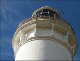 Photograph showing underside of white lantern house. Curved balcony floor bolted to tower wall.