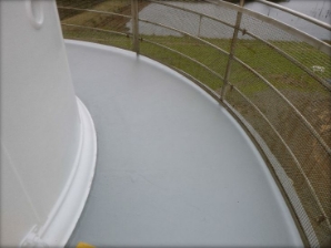 Photograph showing curved, grey balcony floor. Stainless steel balustrade and mesh are fitted to outer edge of balcony floor. 