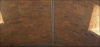 Photograph showing curved, red brick walls. Two window ledges are set into the walls. 