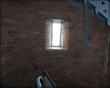 Photograph showing window set into red brick wall. 