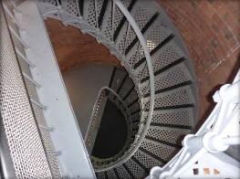 Photograph showing spiral staircase descending to lower floor landings inside lighthouse tower. 