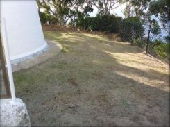 Photograph showing grassy perimeter around base of lighthouse tower.