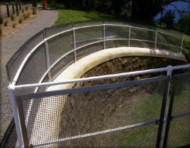 Photograph showing curved retaining wall sloping down from bridge to ground below. 