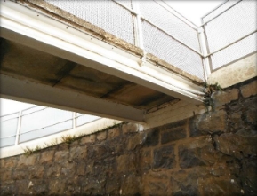 Photograph showing underside of precast concrete slab bridge fixed to edge of retaining wall. 