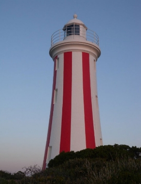 Photograph showing Mersey Bluff Lighthouse - a white lighthouse with red vertical stripes against blue sky. 