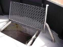 Photograph showing access opening in floor. Mesh cover is propped open.