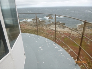 Photograph showing curved balcony wrapped around lantern house. Curved balustrade railing fitted to outer edge of balcony.