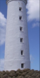 Photograph showing white lighthouse tower. Six window recess are set into tower. 