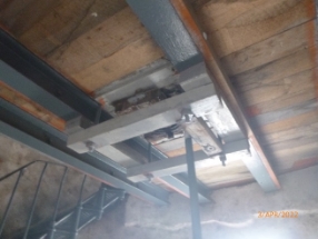 Photograph showing underside of timber floor supported by grey beams. 