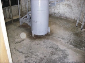 Photograph showing round concrete floor. Grey weight tube fitted to centre of floor. 