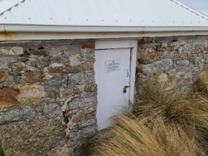 Photograph showing front door of rubble stone building.